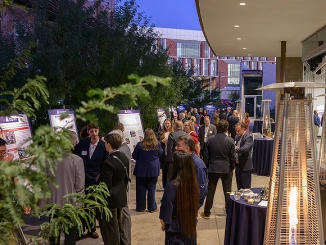 Several people gather at a reception in a courtyard outside the Andrew Weil Center for Integrative Medicine