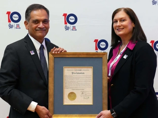A man and a woman stand holding a plaque.